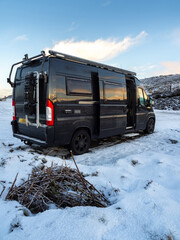 Black campervan overnight parking besides a snowy road on the Isle of Skye after a night of snow
