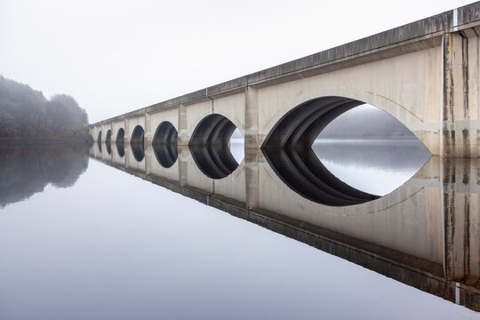 Ethereal view of Ladybower Viaduct in Derbyshire, with its symmetrical arches mirrored in the still reservoir, creating a peaceful and atmospheric scene in the Peak District 