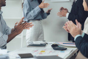 Appreciation and Recognition: A diverse group of professionals applauds a colleague during a presentation, showcasing a supportive and collaborative office culture.