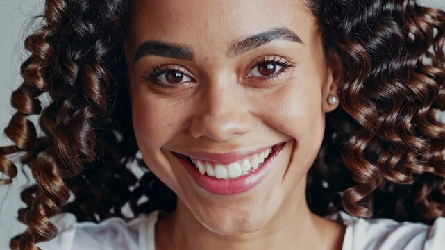 human face expression a potrait of a caucasian latina young woman with curly hair wearing white shirt smiling