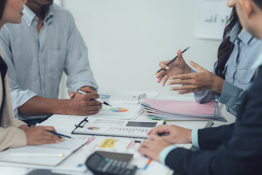 Business Meeting: A diverse group of professionals gather around a table, engaged in a lively discussion, brainstorming and strategizing over business data and financial reports.