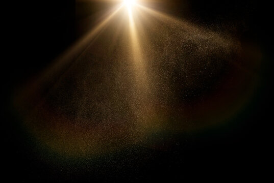 Dust particles shimmer in a radiant sunbeam against a dark background, creating a mystical god rays atmosphere