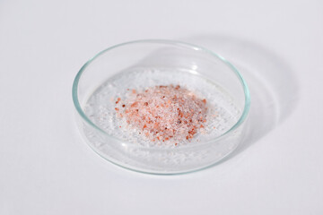 Himalayan salt in a petri dish, white background
