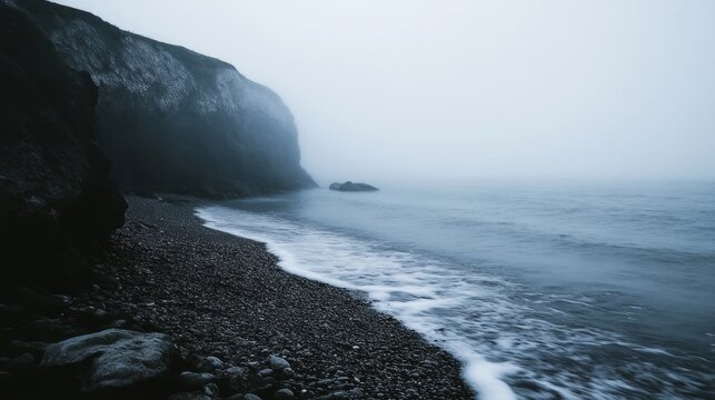 Misty coastline with pebble beach and cliffs in foggy weather - Powered by Adobe