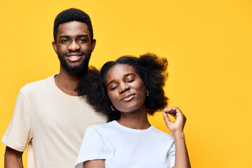 Obraz premium African couple with joyful expressions against a bright yellow background, showcasing love and confidence through their vibrant colors and relaxed outfits