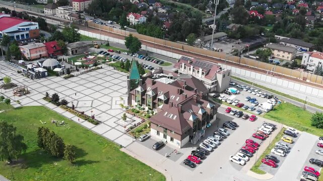Aerial drone footage of the municipal office in Zabierz&oacute;w, Poland. Public building, geometric square, parking area and surrounding urban infrastructure on a sunny day.