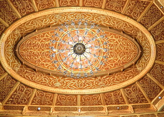Ornate wooden ceiling with intricate carvings and chandeliers, showcasing Islamic architectural...