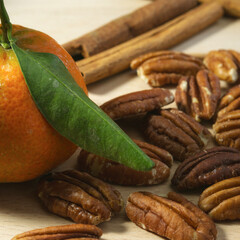 pecan with cinnamon sticks and tangerine on a wooden board close-up