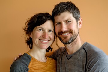 Obraz premium Portrait of a smiling caucasian couple in their 30s sporting a breathable hiking shirt on soft orange background