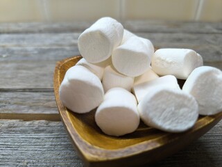 Beautiful, airy, pale white marshmallows on a wooden plate.