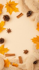 Autumn leaves, pine cones, and cinnamon sticks frame on beige background