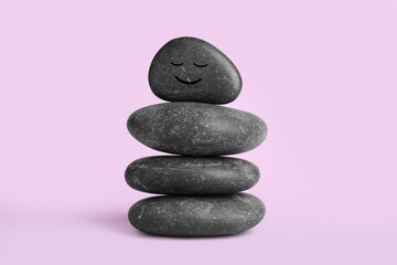 Stack of rocks with drawn smiley face on lilac background. Harmony and life balance
