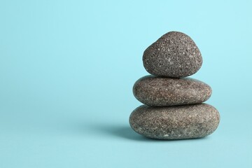 Stack of rocks on light blue background, space for text. Harmony and life balance