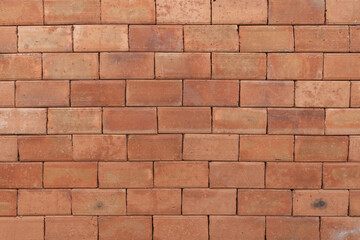 Obraz premium A rustic red brick wall with a weathered texture, showcasing earthy tones and natural imperfections for an industrial look.