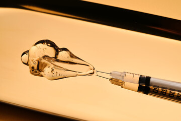 A drop of gel pours from a syringe for cosmetic procedures.