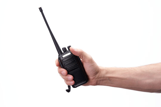 A black walkie-talkie is held in the hand on a white background.