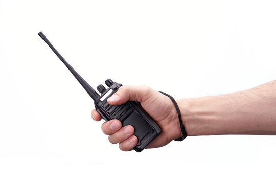 A black walkie-talkie is held in the hand on a white background. - Powered by Adobe