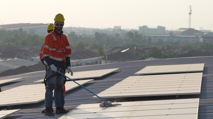 A technician inspects and repairs solar panels on a rooftop installation. The worker wears protective gear and focuses on ensuring the system is functioning well. The sky is clear and bright.