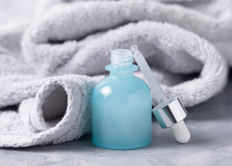 Pipette set near an opened blue dropper bottle near light gray bath towel close up, cosmetic mockup