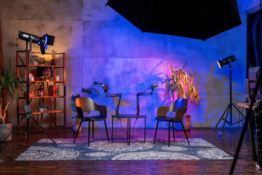 Modern podcasting setup featuring microphones and chairs in a stylish broadcast studio