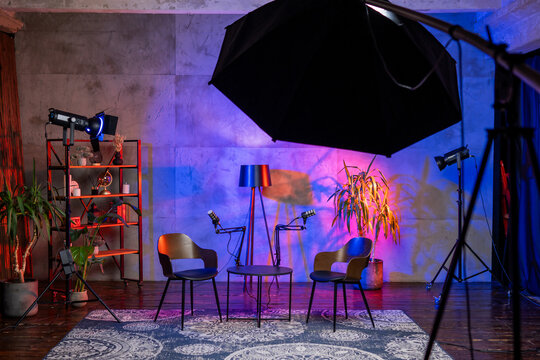 Podcast studio setup featuring microphone, chairs, and colorful lighting for interviews and broadcasts