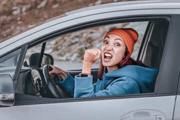 Angry female driver shaking fist at another car while driving