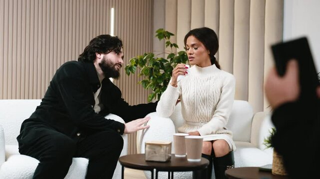 A man apologizes to his wife as she cries during a therapy session. Concept: emotional support and relationship healing through sincere apologies and professional guidance.