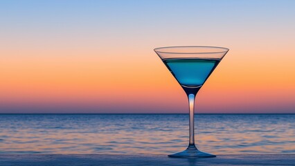 A classic martini glass filled with a bright blue ocean cocktail.  A lonely sea with a sunset on a glass shelf Silhouettes creates a background for a timeless poetic composition.