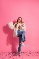 Young fashionable woman in a pink-themed stylish outfit enjoying music and celebrating elegance and...
