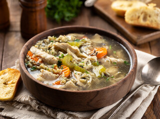 Bowl of chicken and rice soup on wooden table