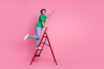 Full body photo of attractive young woman climb ladder dressed stylish green clothes isolated on pink color background © deagreez
