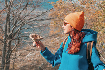 Happy forager showing freshly picked mushroom during a sunny autumn day in the woods