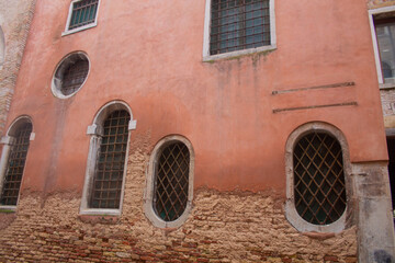 Facade of an old Italian brick house with square and rounded windows with lattice in Venice, Italy