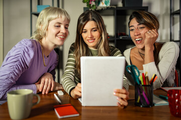 Three young women studying together in a creative workspace, teamwork and learning concept