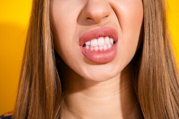 Close-up of a young woman making a funny facial expression against a yellow background
