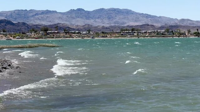 Powerful wind gusts whip Lake Havasu's surface, generating choppy waves and foamy white caps, showcasing nature's raw energy in this popular Arizona waterway.