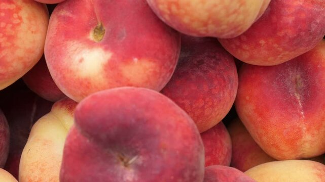 Pesche Tabacchiere, a unique variety of flat peaches, on display at an Italian market, highlighting the tradition and freshness of Italian summer produce.