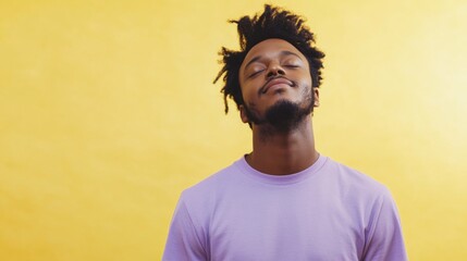 Obraz premium Calm adult African American man with curly hair in purple t-shirt practicing meditation with closed eyes on vibrant yellow studio background