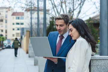 Businesspeople working with laptop outdoors in urban environment