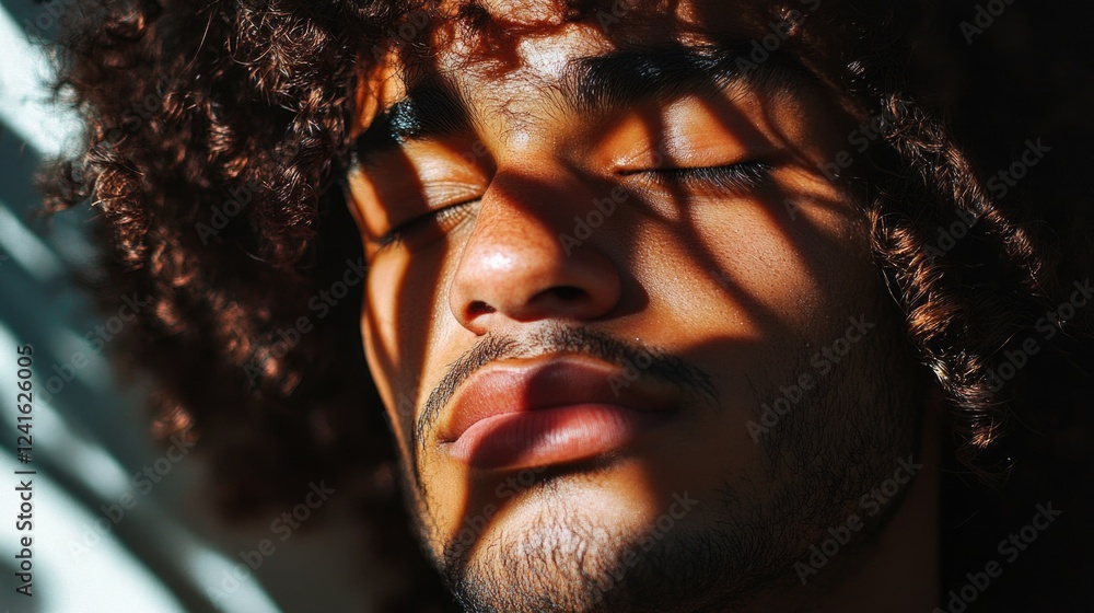 Poster young man with curly dark hair relaxing with eyes closed under soft shaded light creating intricate 
