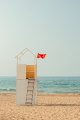 A white wooden tower on an empty sandy beach by the sea. Lifeguard station.