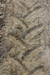 Tractor tire track imprint in dirt road. Agricultural tractor tire tread marks in dried mud forming a distinctive pattern on a dirt road.