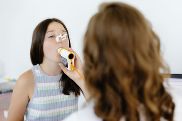 Girl testing breathing function by spirometry in doctors office. Diagnosis of respiratory function...