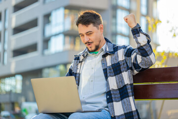 Overjoyed happy mature man working on laptop netbook screaming in delight triumph winner gesture...