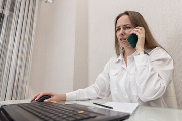 Female person office worker or freelancer concentrated works in office or at home at computer, talking on mobile phone. Business woman, successful entrepreneur solving important issues while working. 