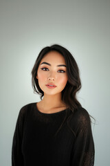 young woman with wheat colored skin and long, dark hair gazes directly at camera, exuding confidence and poise. Her makeup is subtle yet enhances her features beautifully