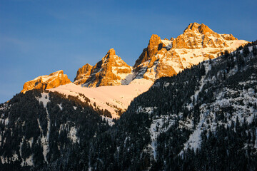 The sun setting on a snow covered rocky mountain peak in the French or Swiss Alps.