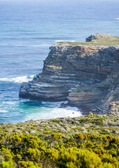 Rocky outcrop and sea cliffs next to the ocean in South Africa with a a small bay and beach in view