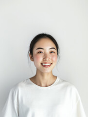 smiling young woman with natural look, wearing white shirt against plain background. Her joyful expression radiates confidence and warmth