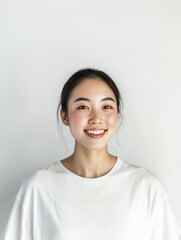 smiling young woman with clear skin and freckles, wearing white shirt against plain background, exuding confidence and warmth